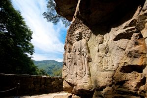 Rock carved triad Buddha